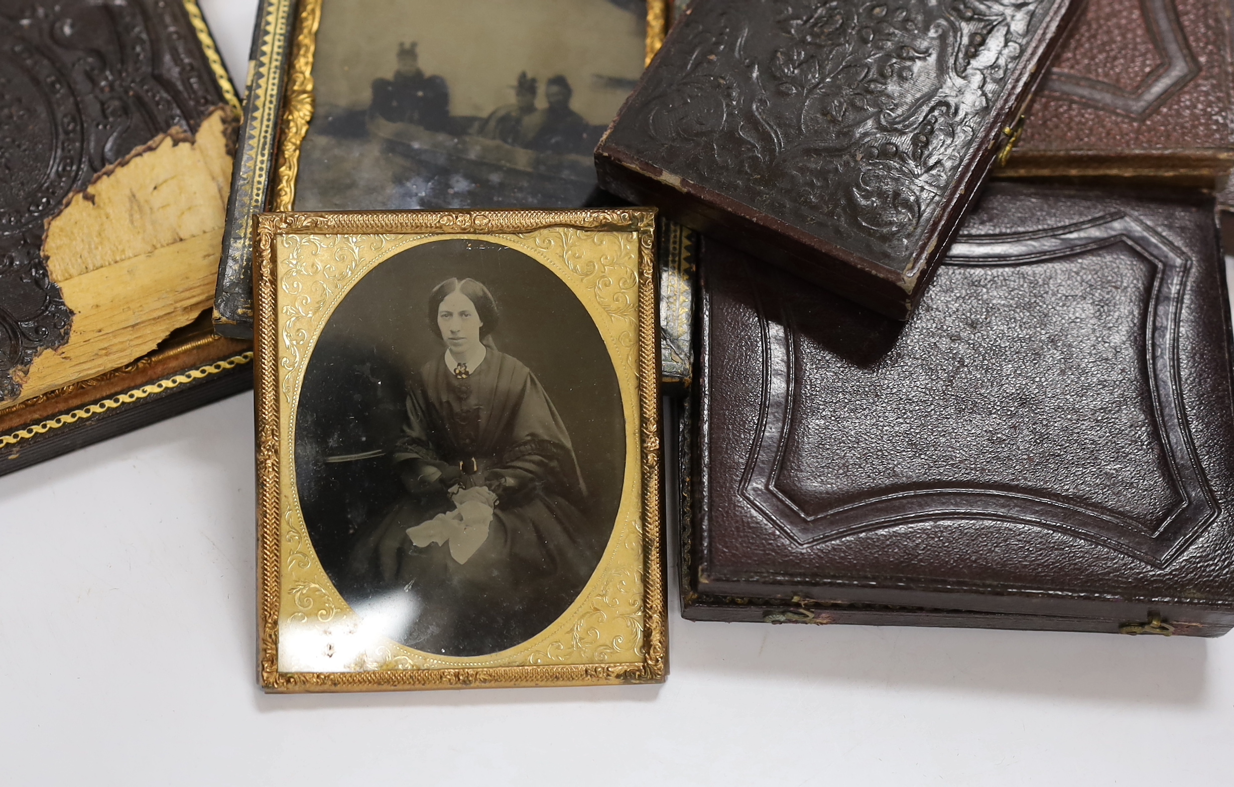 A collection of mid 19th century ambrotype portrait photographs, all mounted in brass etc frames, some in decorative cases, two examples framed (25)